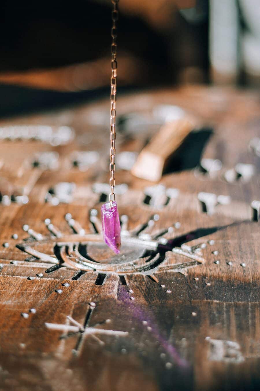 An amethyst point suspended over a carved pendulum board